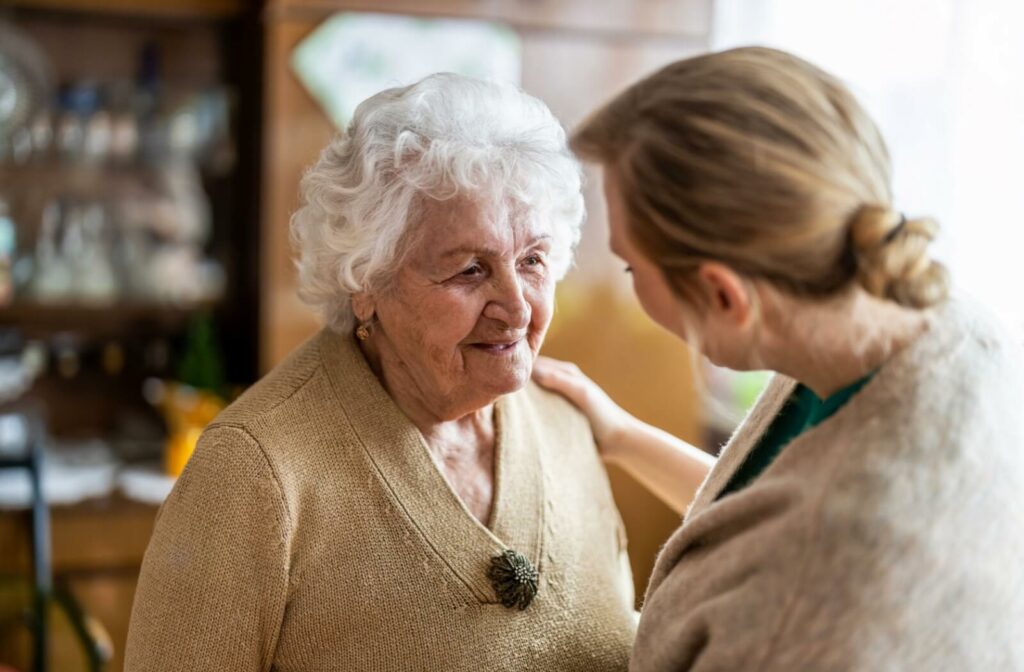 An older adult woman talking to a nurse in a memory care facility