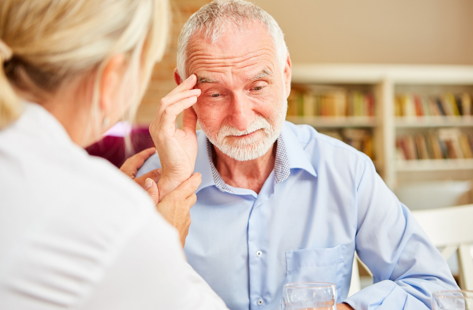 A doctor examining an older adult man who has signs of disorientation.