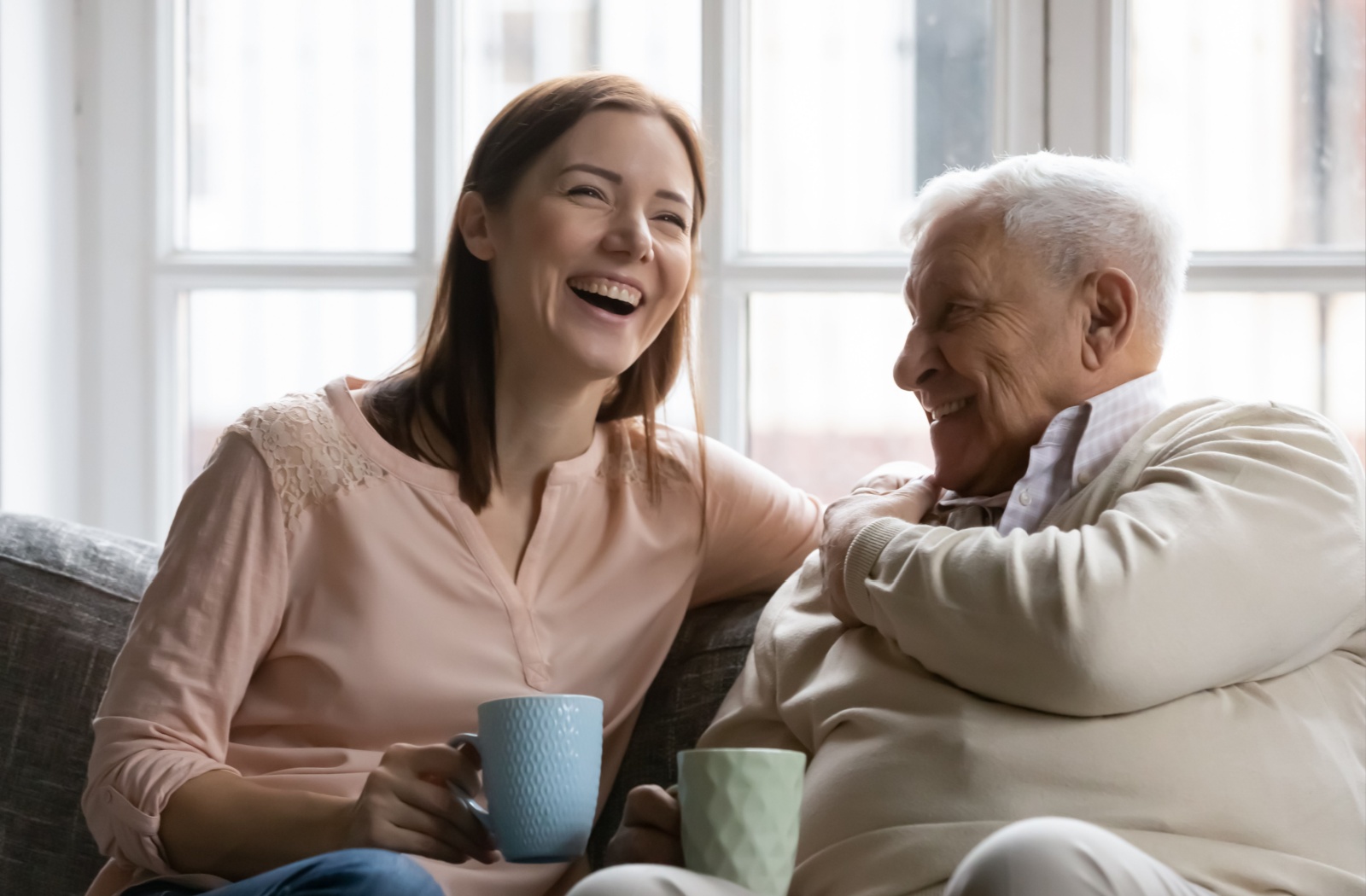 A woman shares a laugh with her senior father while visiting him in memory care.