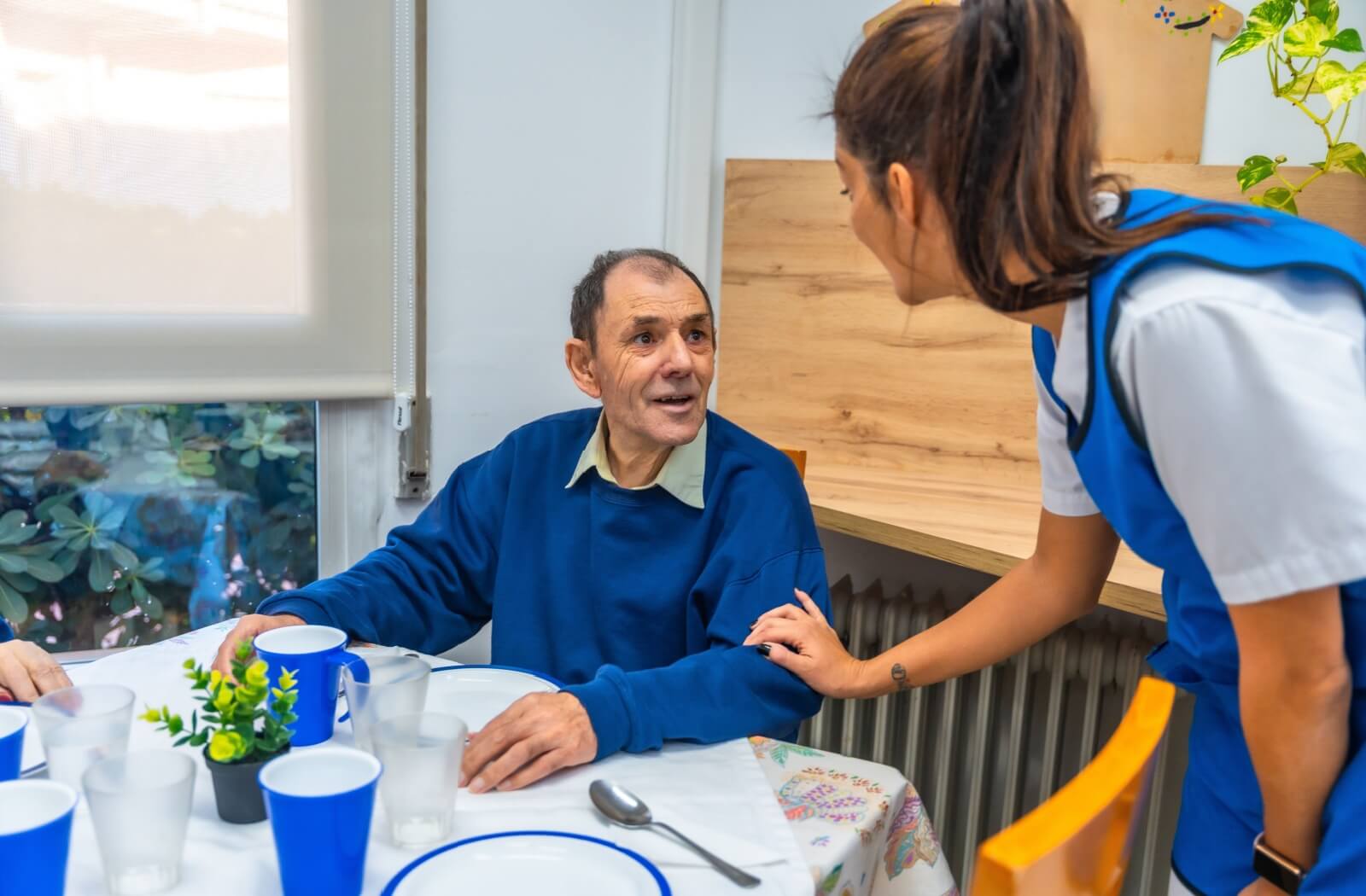 A memory care nurse visits with a senior resident as they prepare for breakfast.