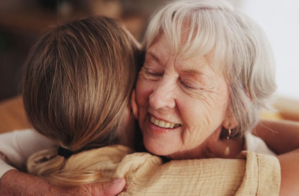 A senior resident hugs their adult child during one of their weekly lunches, both smiling.