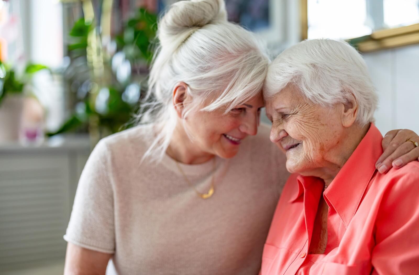 A person embraces their parent with dementia while visiting them in memory care.