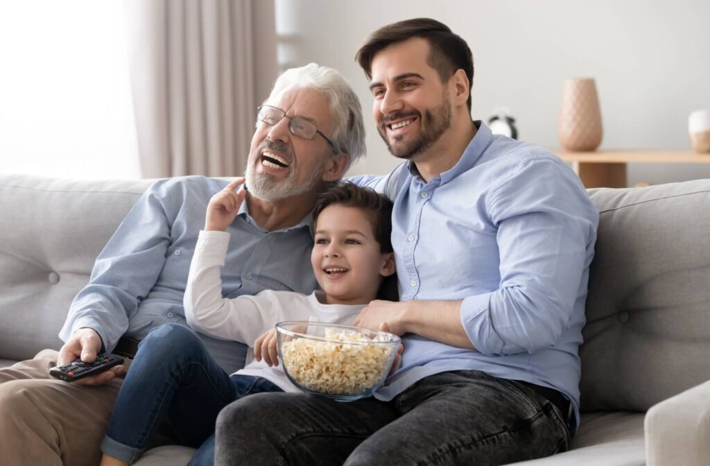 A multigenerational family eats popcorn and watches TV together.