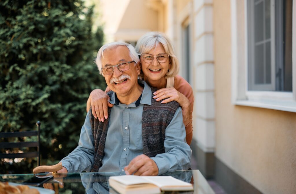 An elderly couple smiling at a table in a memory care community.