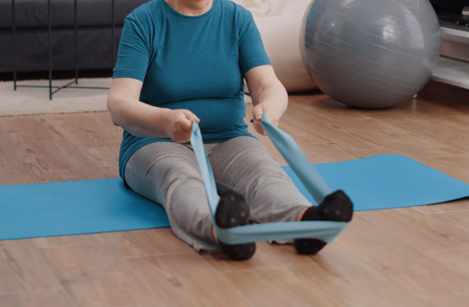 A close-up image of a senior performing a seated row with a resistance band.