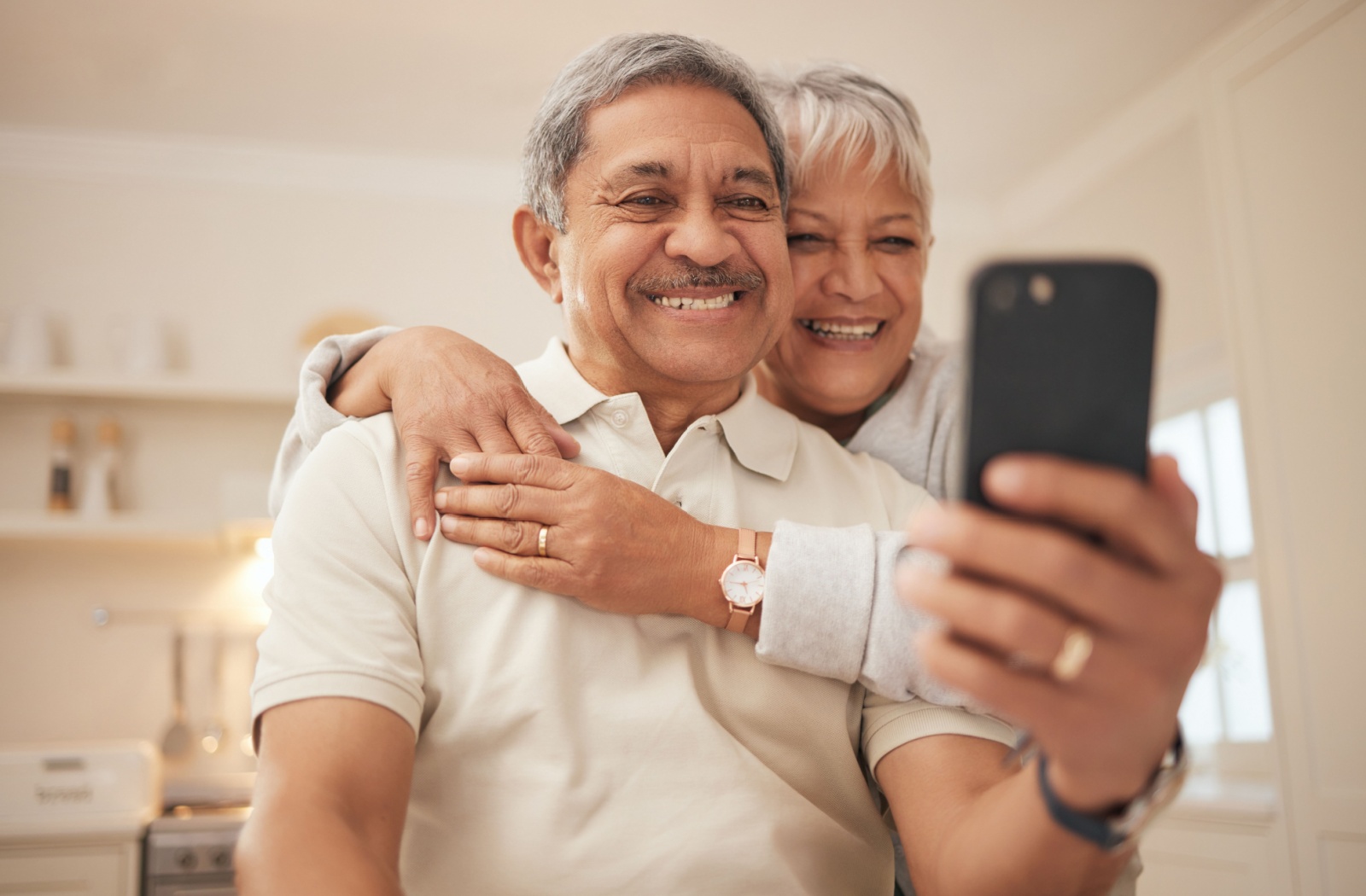 An elderly couple video calling with a loved one on a smartphone.