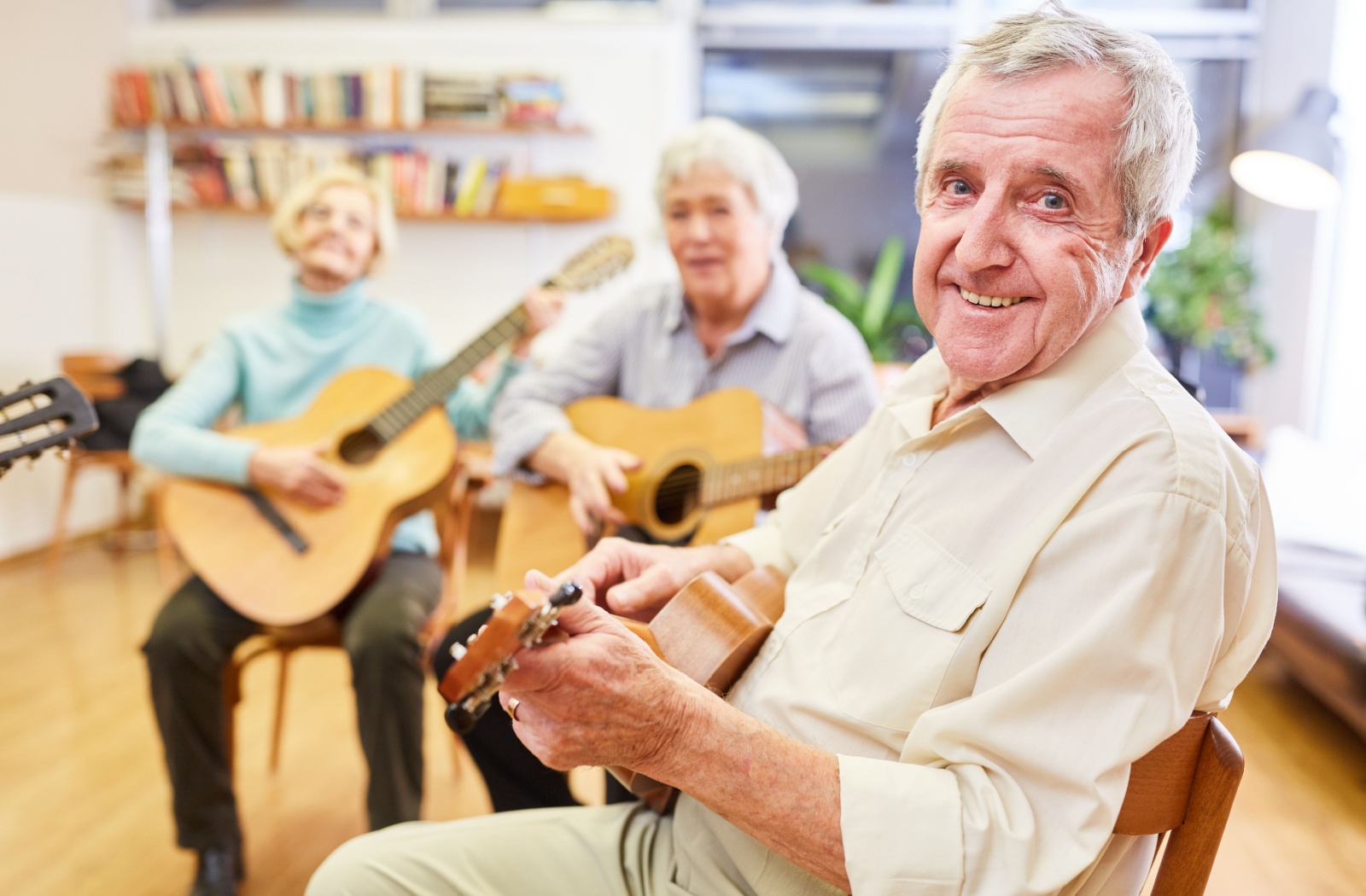 Group of older adults playing guitars together during a memory care music therapy session for seniors with dementia
