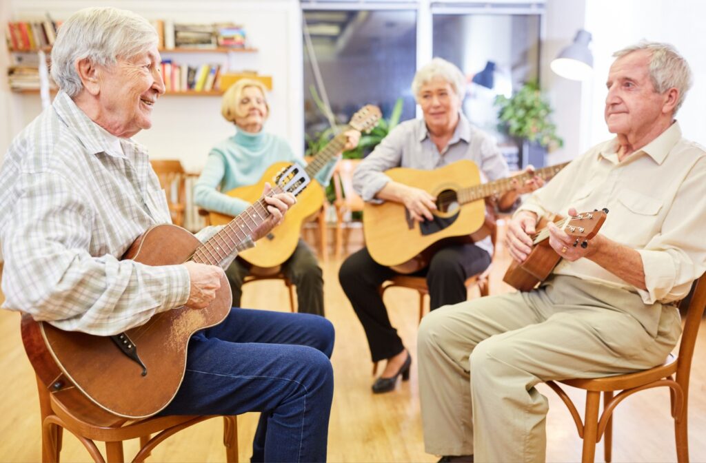 A group of seniors sit in a circle with guitars, playing and learning chords as part of music therapy in memory care