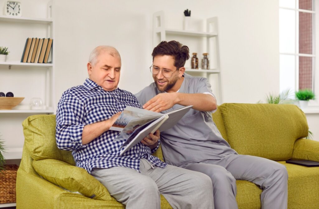 An elderly man going through his family photo album with a male caregiver.