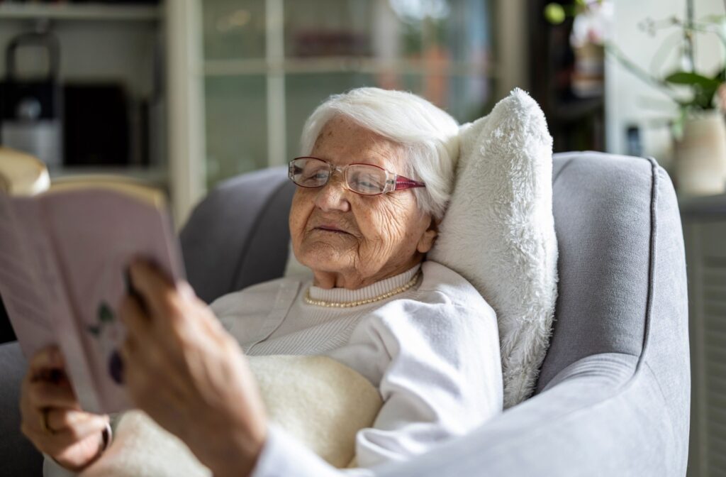 A senior relaxes in a cozy chair with a soft blanket while reading a book in a private space during respite care